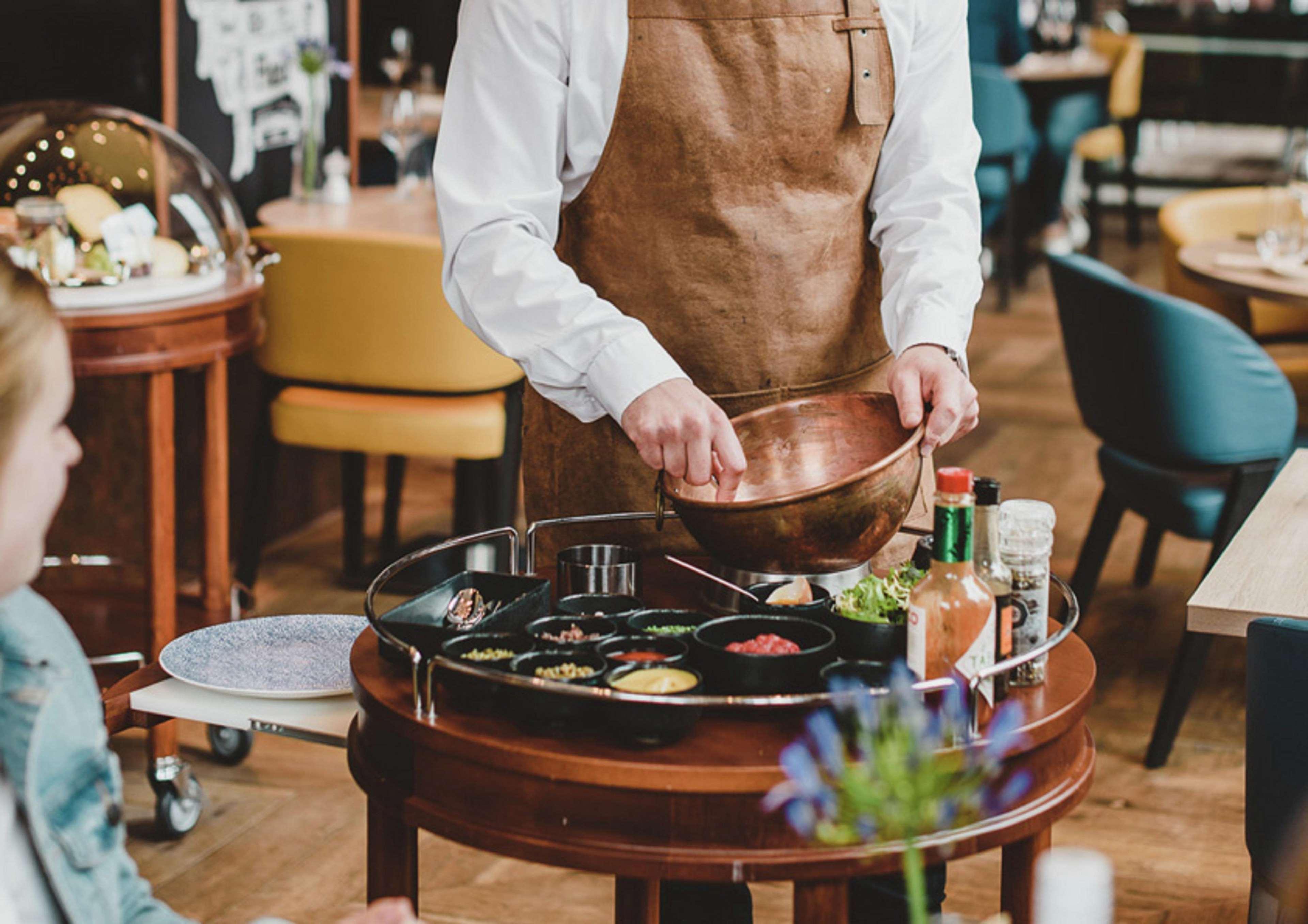 Hilton The Hague Hotel Exterior photo A server prepares a dish at a restaurant